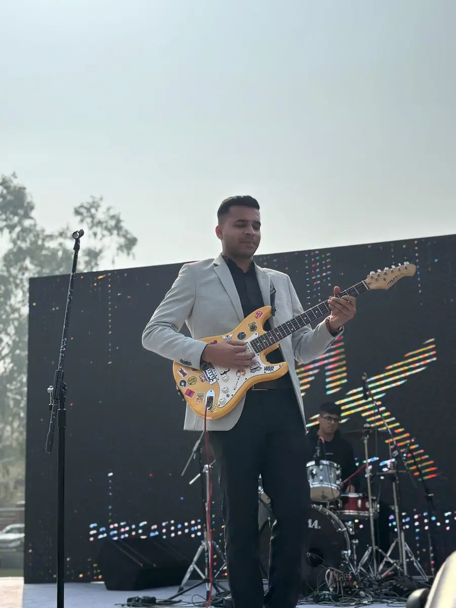 A Musicphonetics performer playing electric guitar on stage with a drummer behind