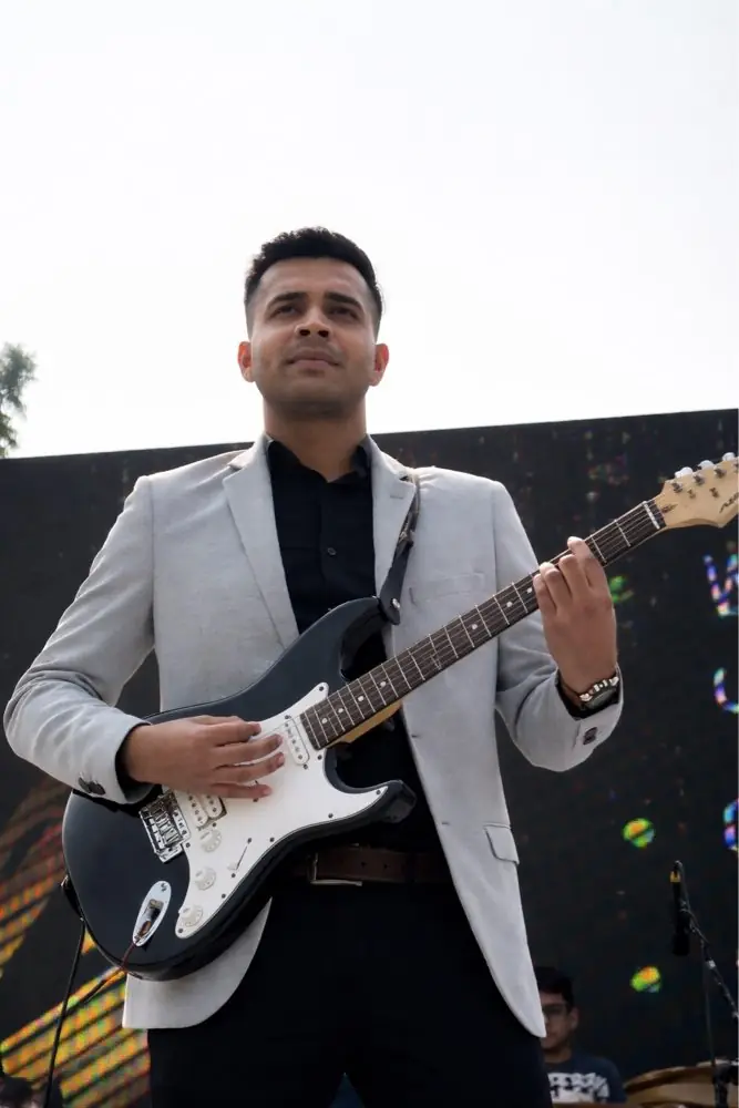 A Musicphonetics performer on stage with an electric guitar under the lights